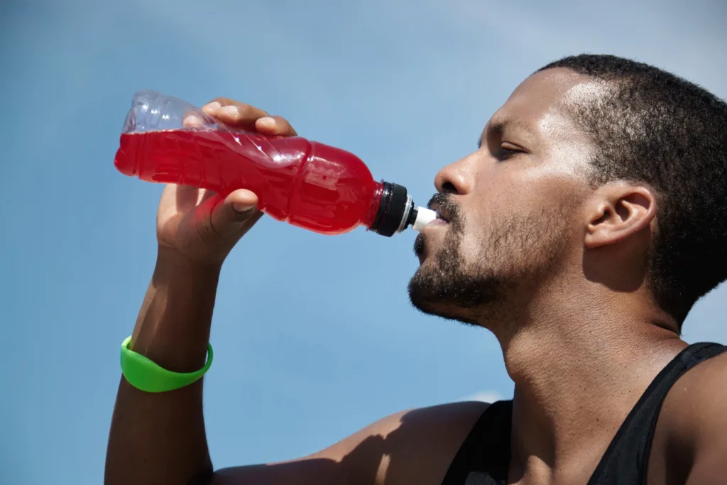 jovem atleta se hidratando com uma bebida vermelha.