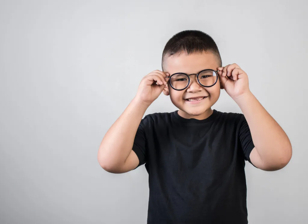 Um jovem asiatico sorridente, seguranddo seus oculos.