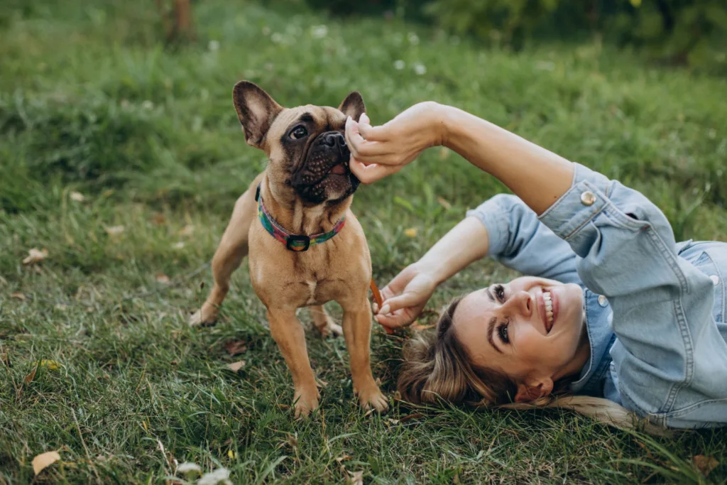uma linda jovem deitada em um parque brincado com seu cão.
