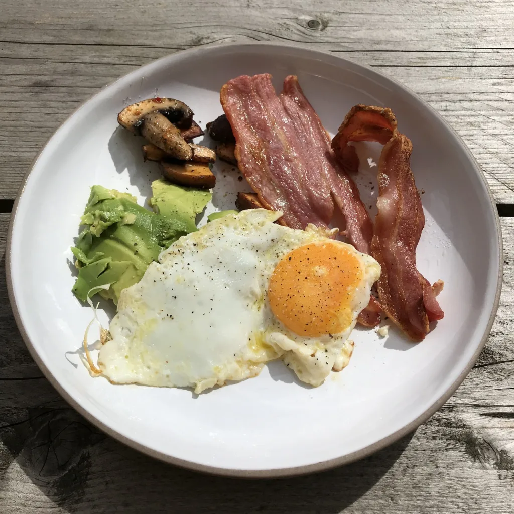 prato de um café da manha da dieta cetogenica, composto de ovos, bacon e brócolis.