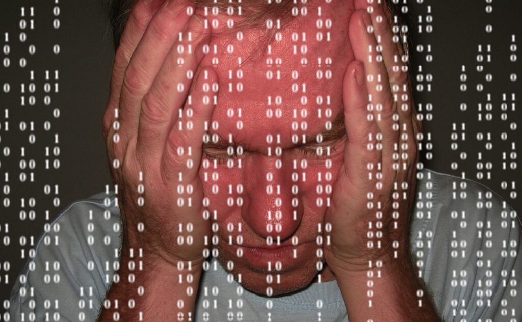 um homem apoiando a cabeça com as duas mãos em sinal de desespero e números caindo na tela em primeiro plano.