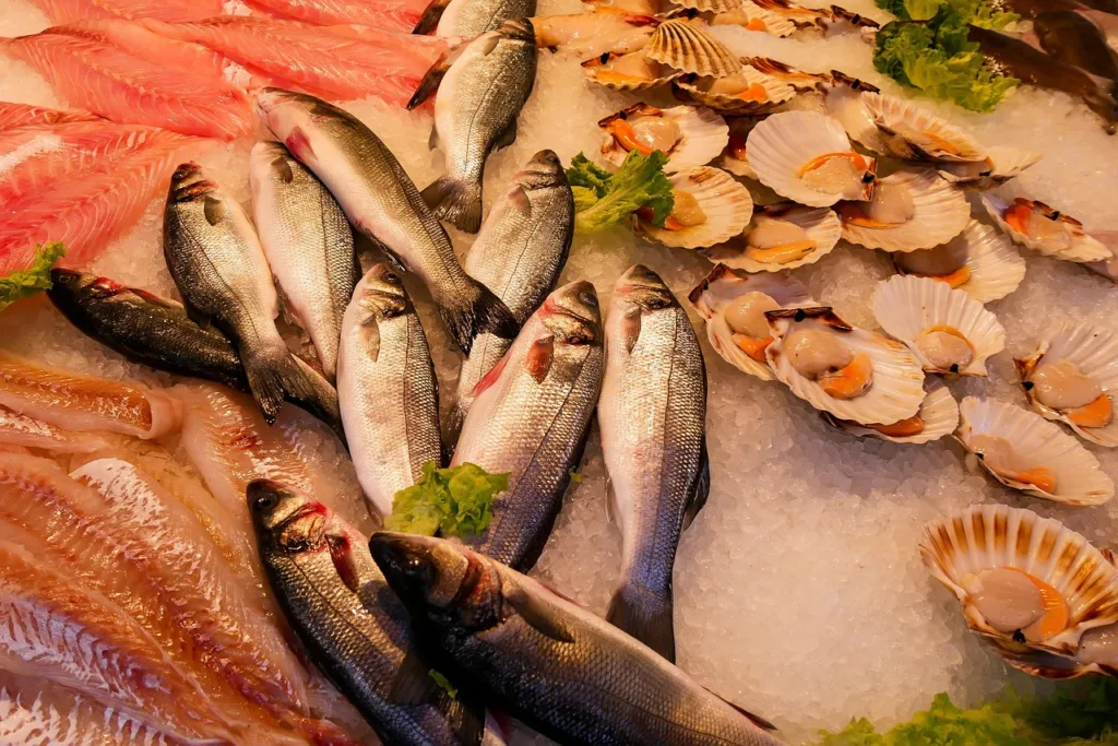 vários tipos de peixes e mariscos num balcão de supermercado.