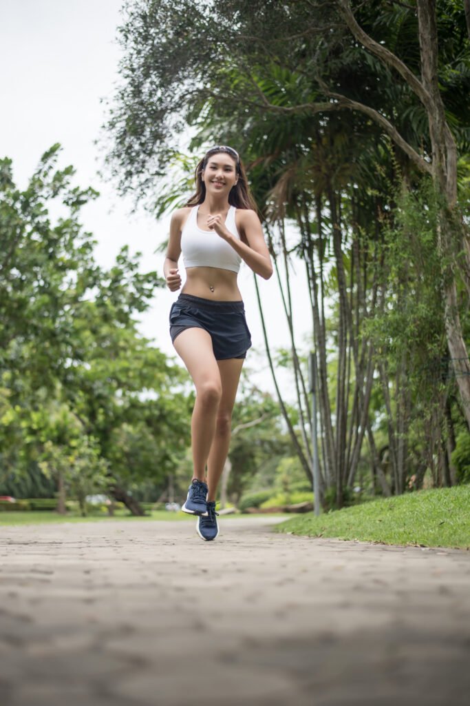Uma jovem atleta correndo num local arborizado.