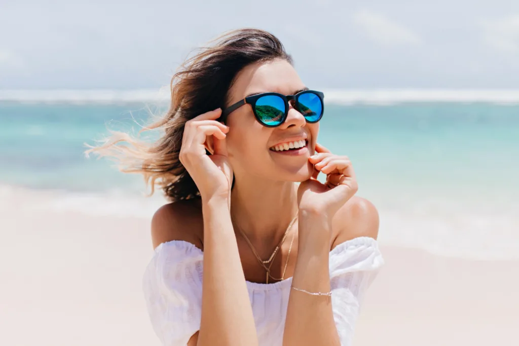 uma linda jovem de oculos de lentes azuis numa praia.