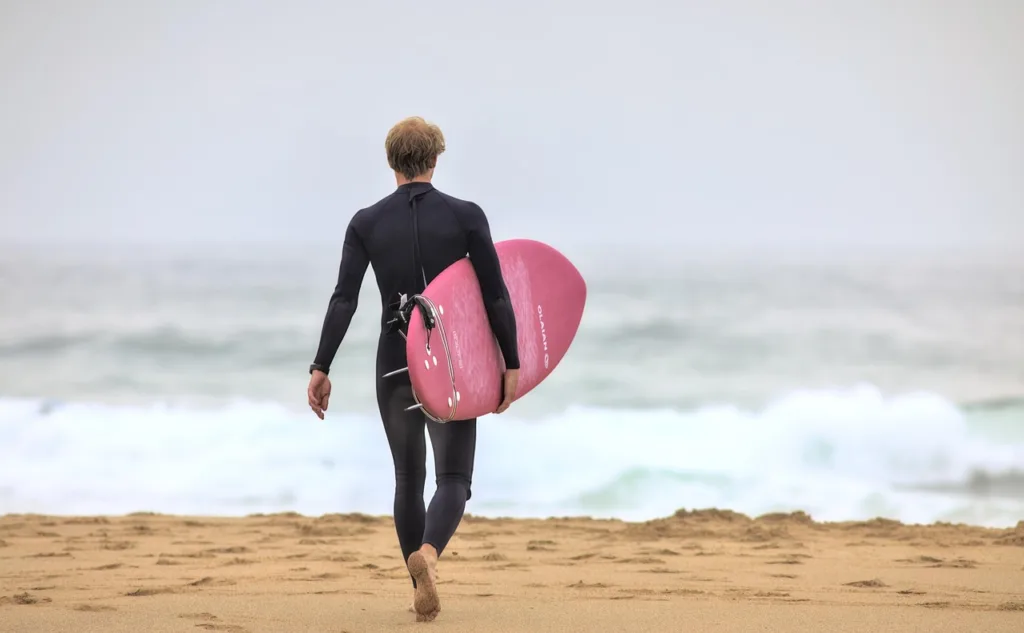 um surfista com sua prancha caminhando em direção as ondas.