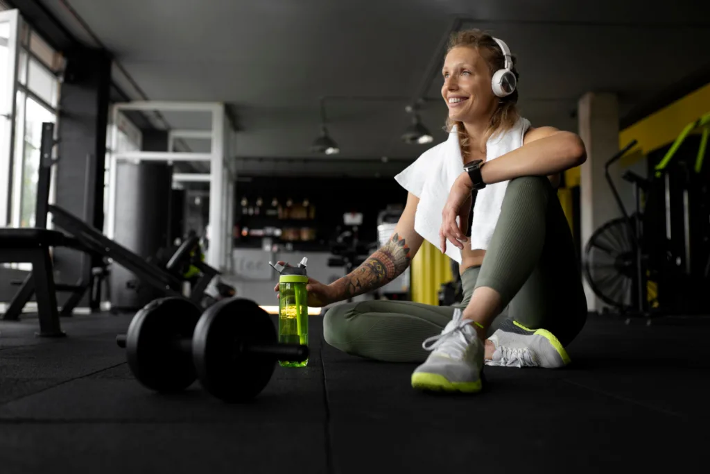 uma atleta sentada no chão da academia, descansando.