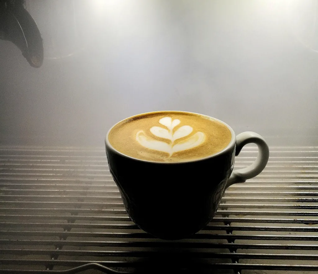 xicara de café com uma arte de leite na figura de uma flor.