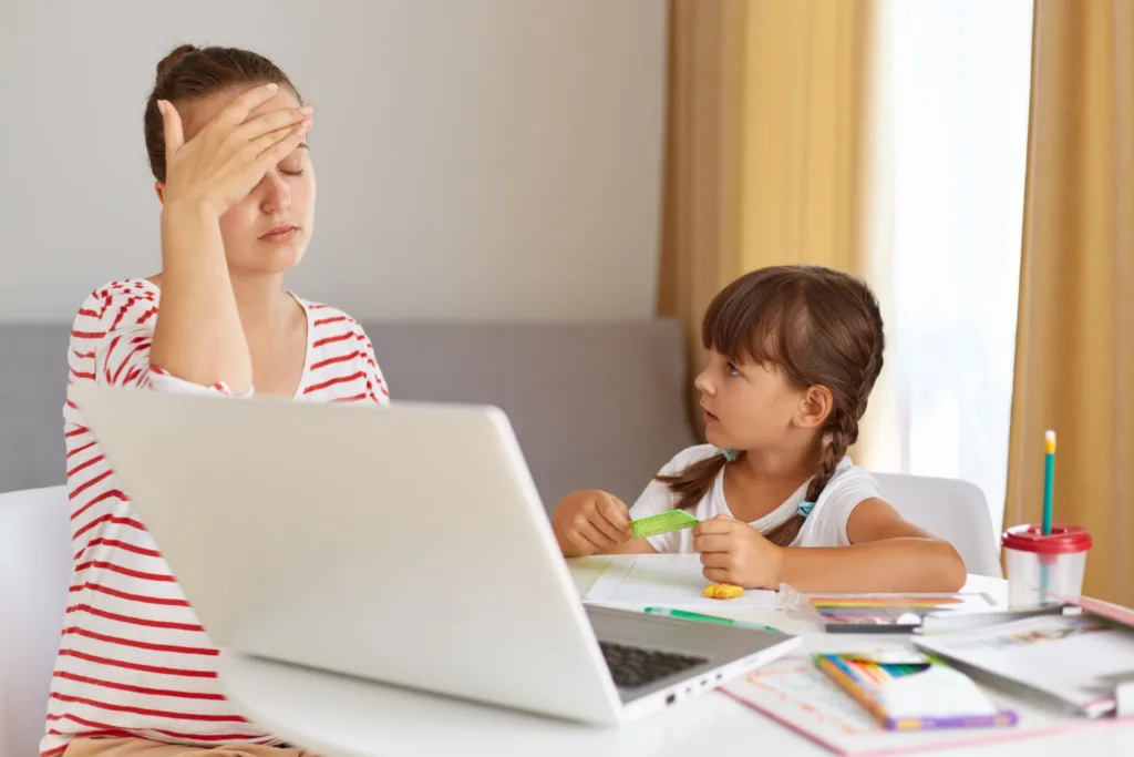 Uma jovem mãe com dificuldades de concentração ao ensinar a filha em frente a um computador pessoal.