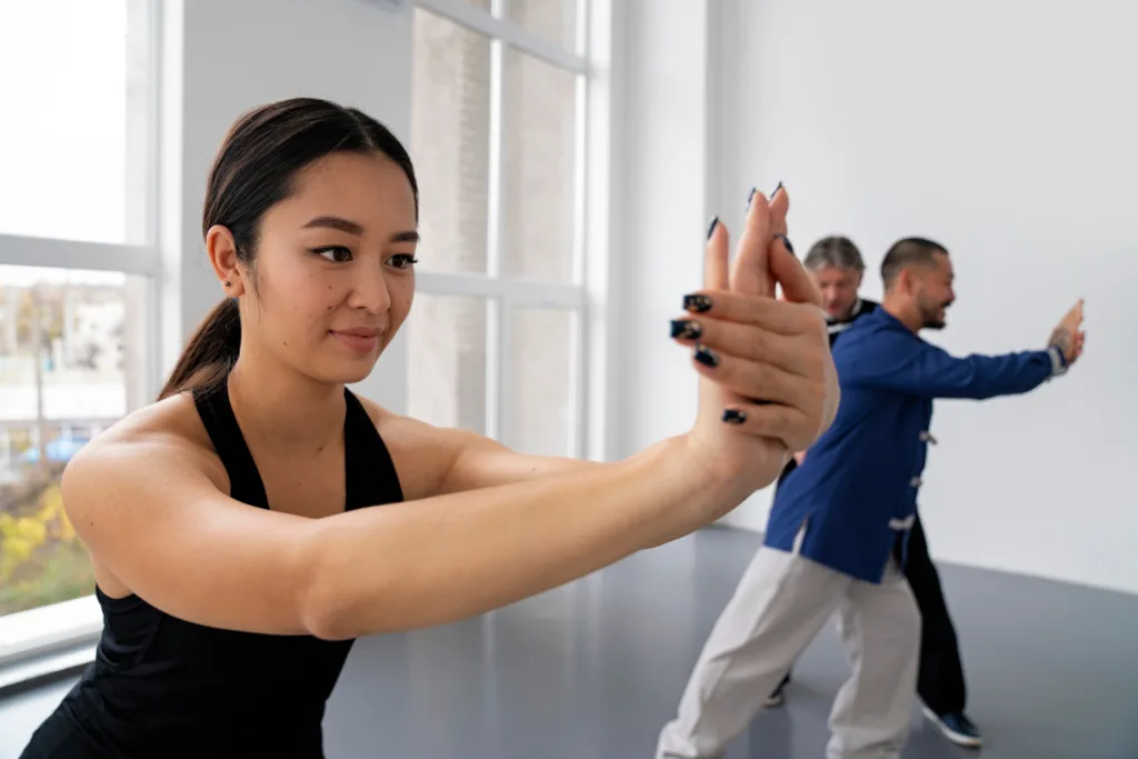 mulher oriental fazendo alongamento dos braços, durante pratica do Tai chi.