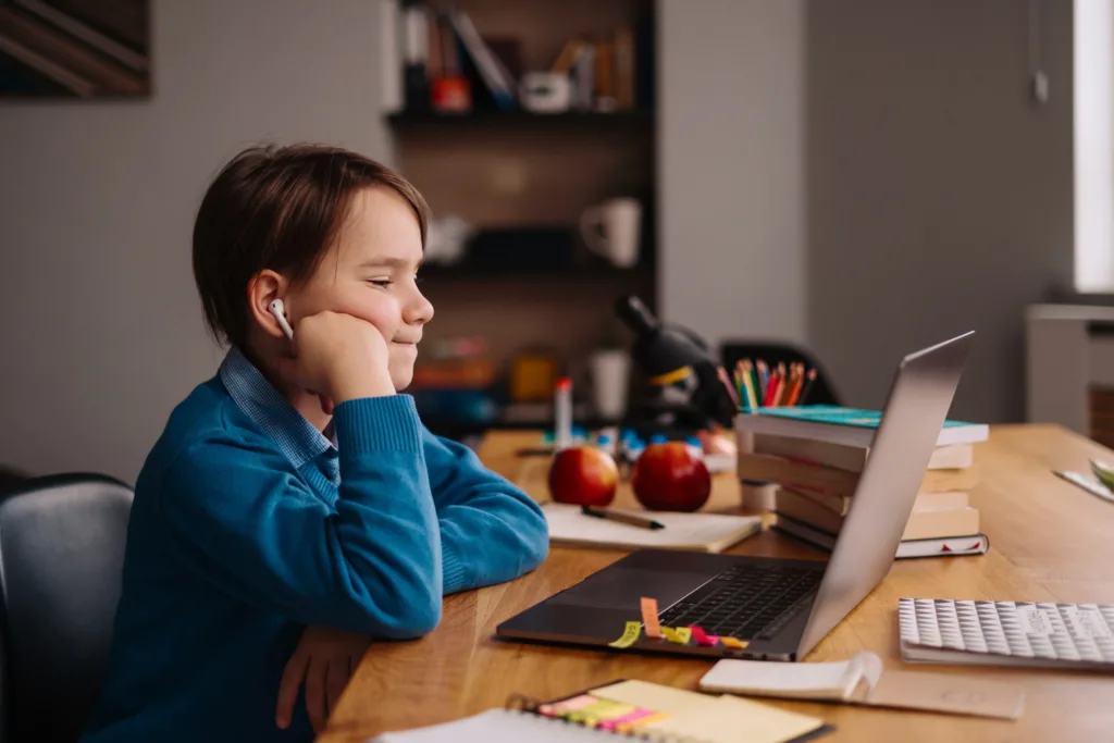 Um adolescente com dificuldades  de concentração ao fazer as tarefas da escola em um notebook.