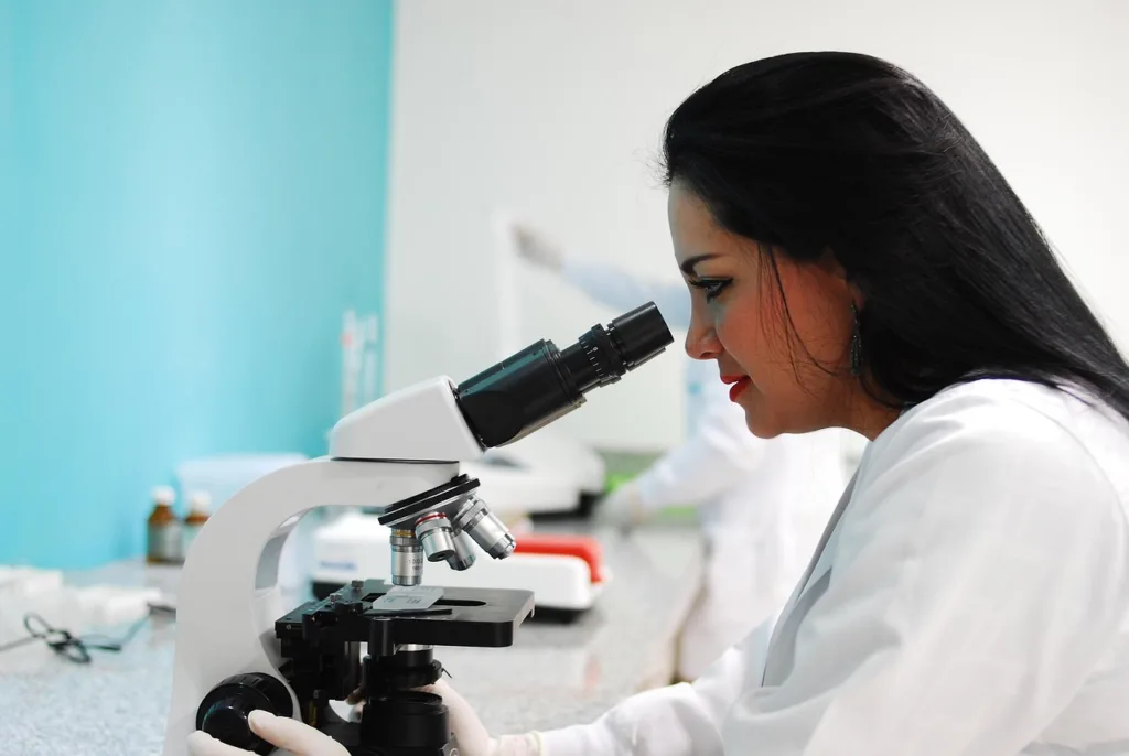 Uma cientista observando em um microscópio, num laboratório.