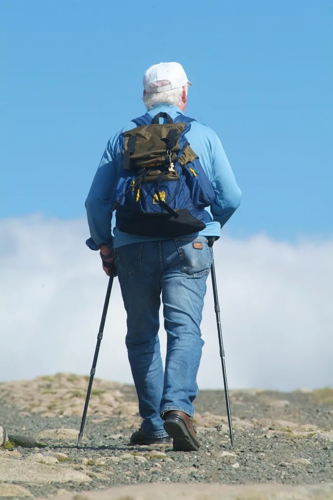 homem fazendo caminhada nórdica,  em uma montanha,  visto pelas costas.