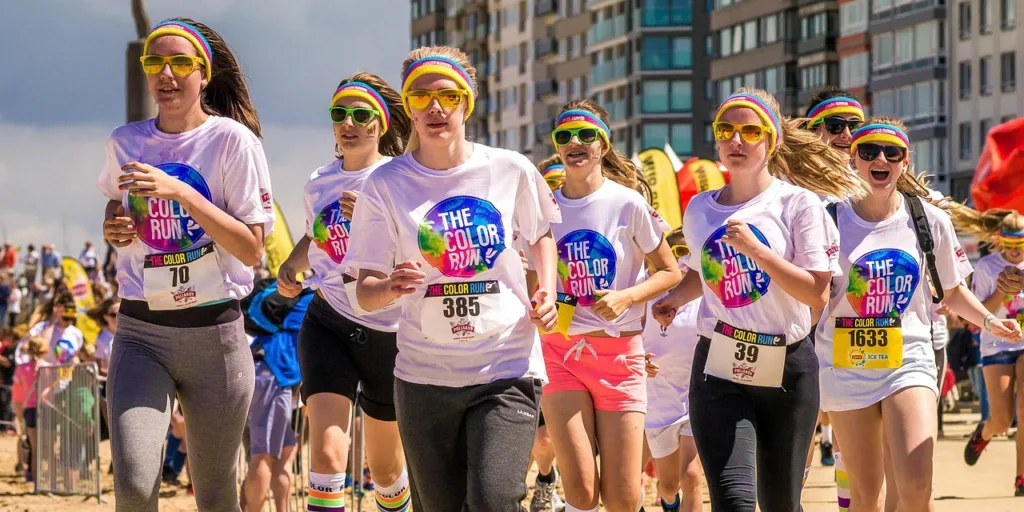 jovens participando de uma corrida de rua com camiseta brancas e oculos coloridos.