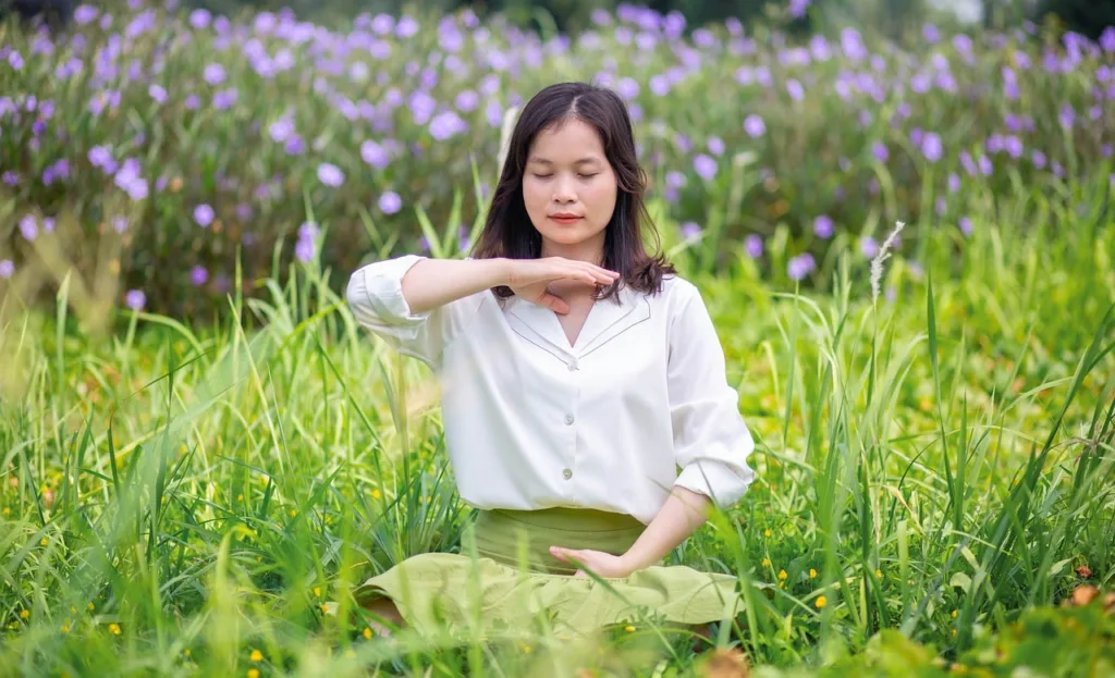 uma jovem oriental fazendo yoga num jardim gramado.