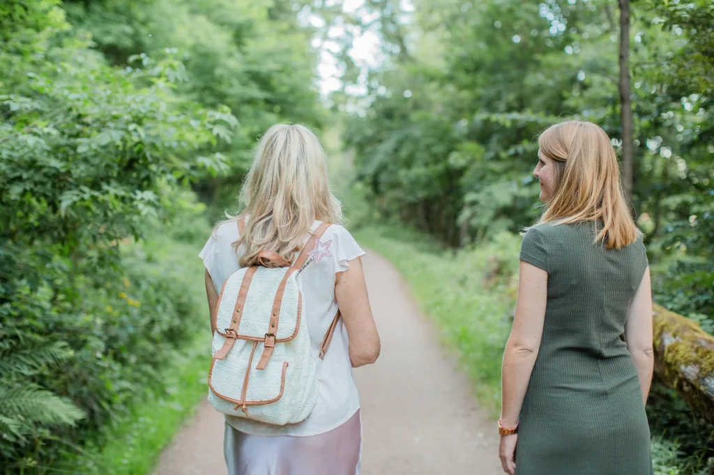 duas mulheres fazendo caminhada em uma floresta, vistas pelas costas.