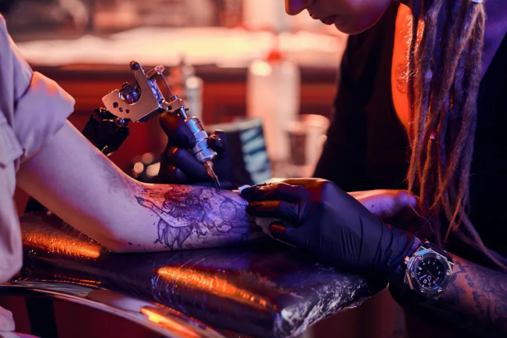 um tatuador, tatuando um braço.