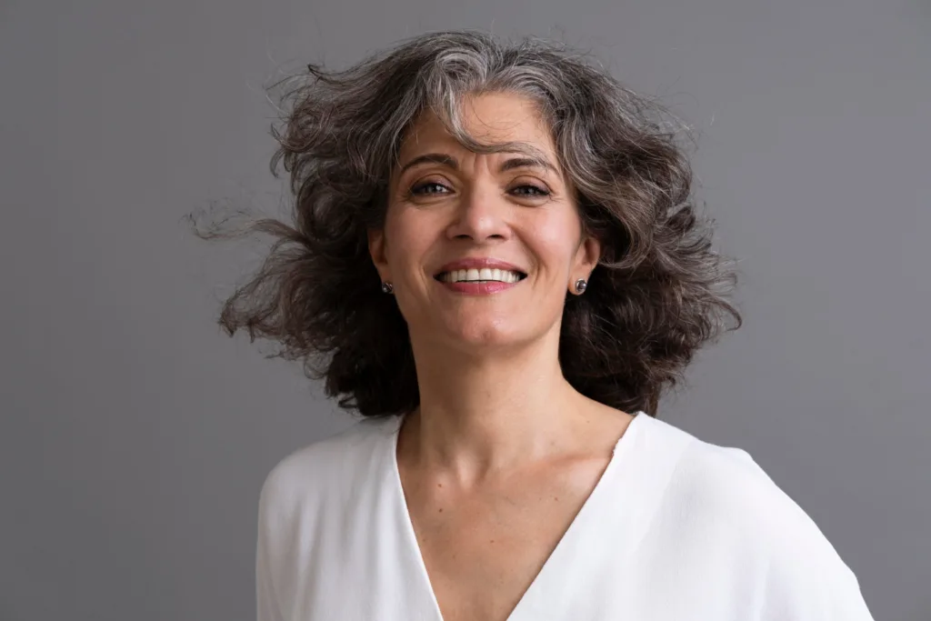 mulher de meia idade, com cabelos grisalhos, sorrindo.