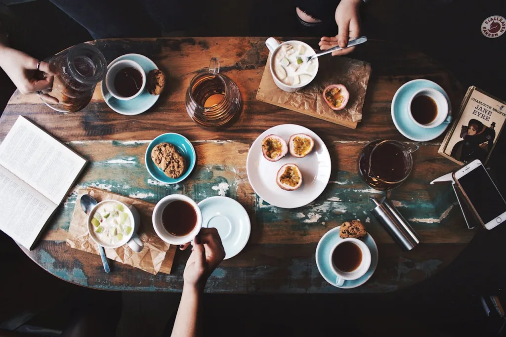 mesa de lanchonete com diversas xicaras de café, chá e petiscos.
