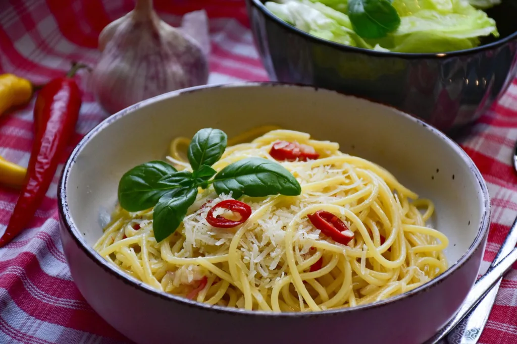 prato de espaguete com fatias de tomate e uma flor de manjericão.