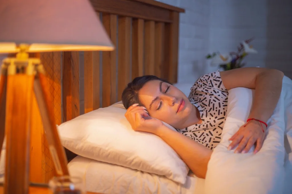 mulher acima dos 45 anos dormindo de lado em uma cama de madeira.