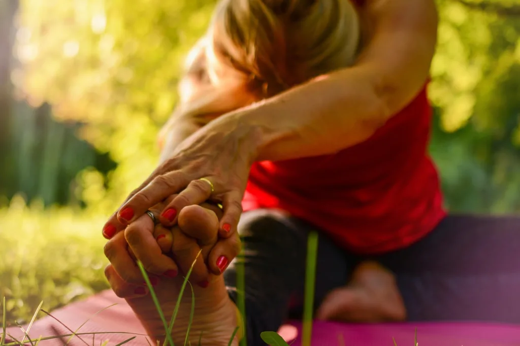 uma senhora fazendo alongamento de yoga ao ar livre.