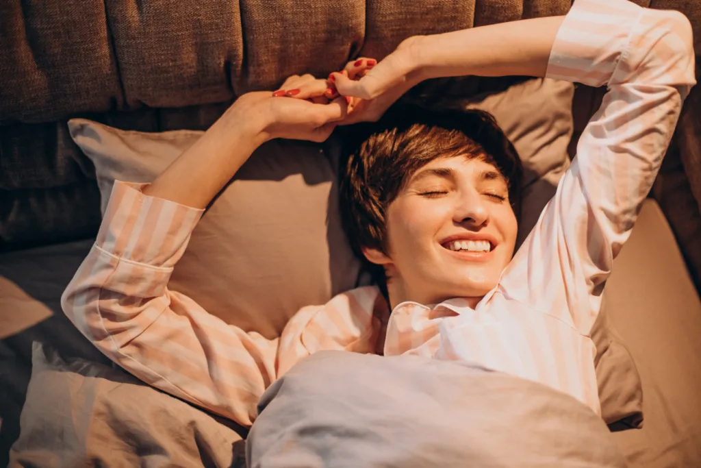 uma jovem de pijama bege acordando de um sono revitalizante.