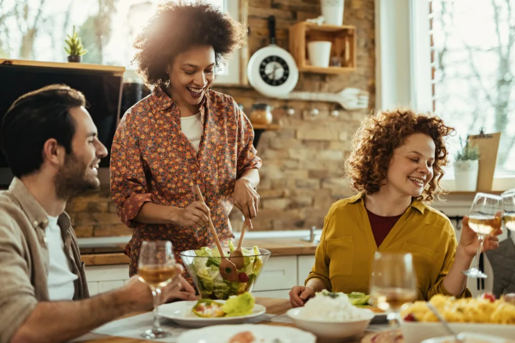 três jovens felizes, almoçando em uma mesa.