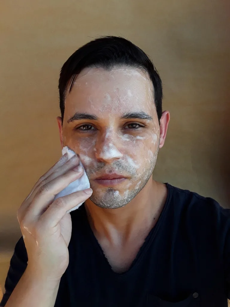 um jovem lavando o rosto com sabão.