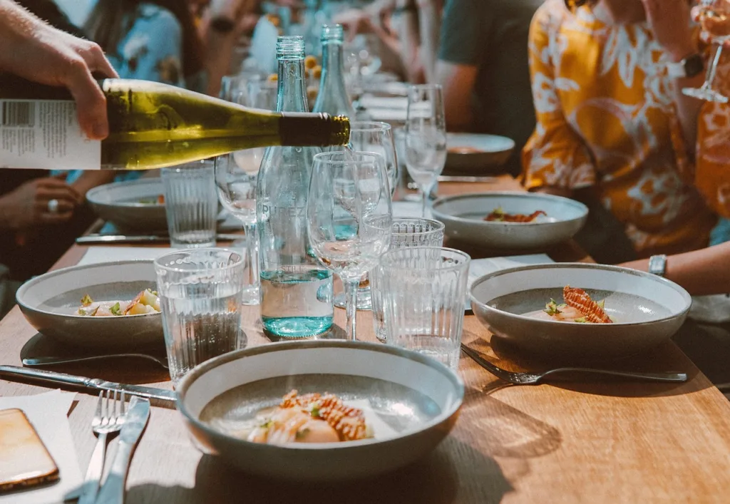 mesa posta de jantar servindo vinho em uma taça.