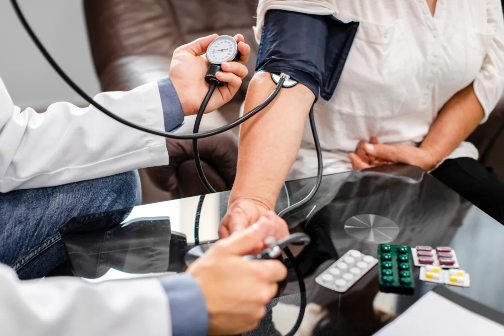 medico aferindo a pressão de um paciente no consultório.