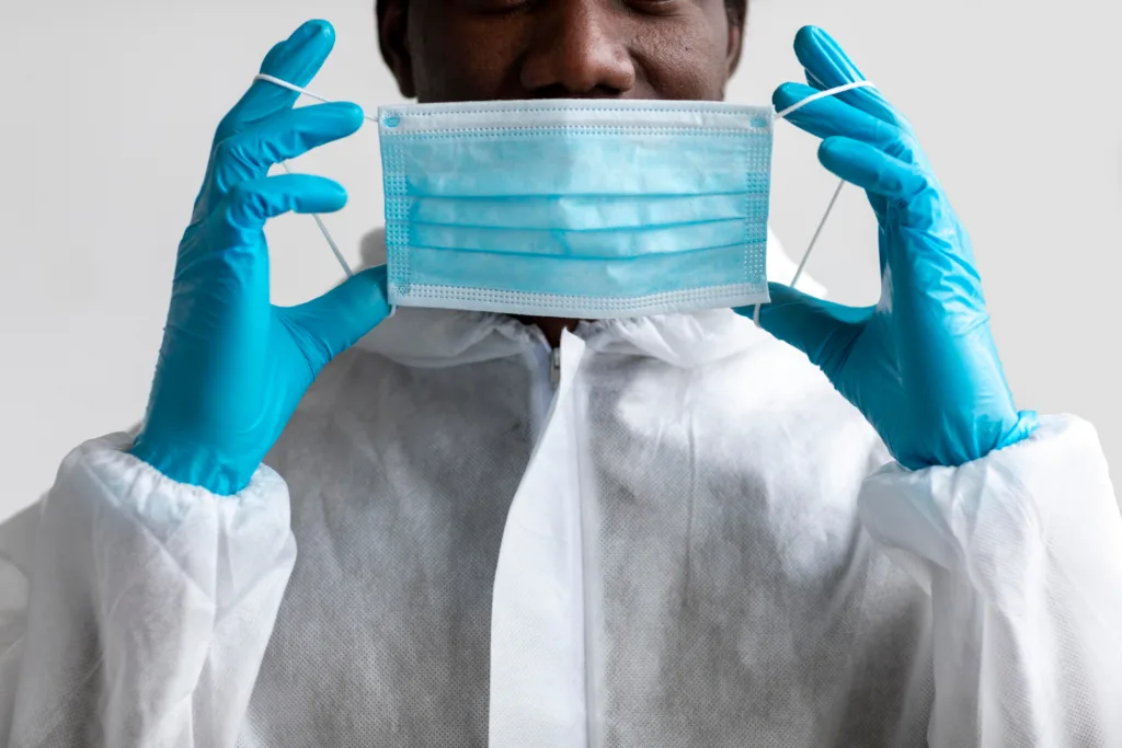 Cientista paramentado com luvas e mascara. 