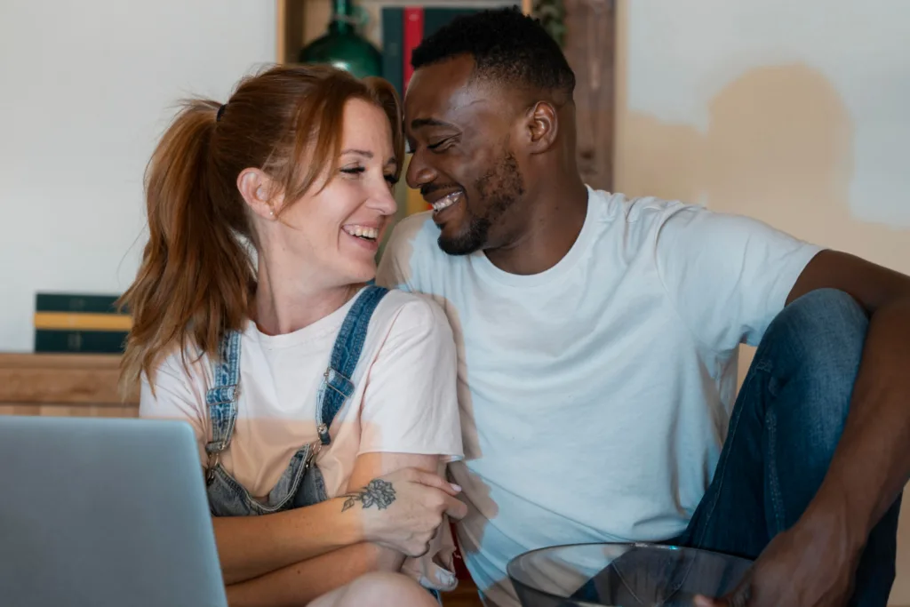 casal feliz diante de uma tela do laptop.