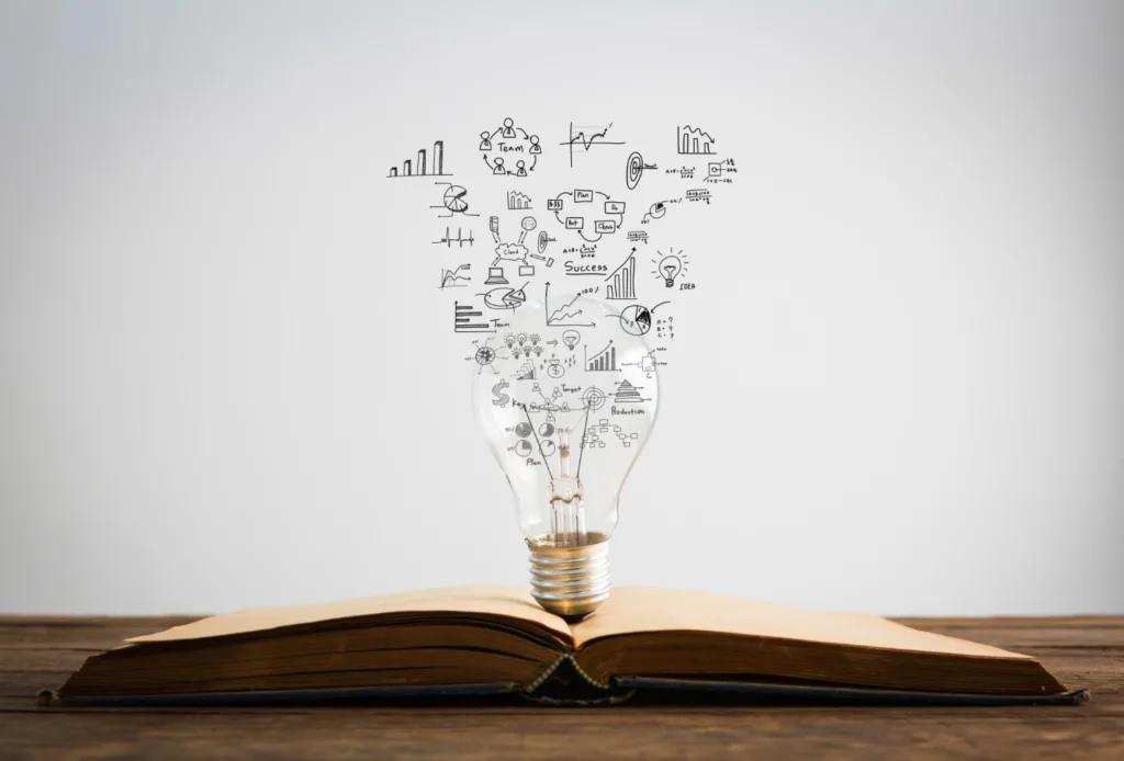 Arte de um livro aberto com uma lampada retirando ideias.