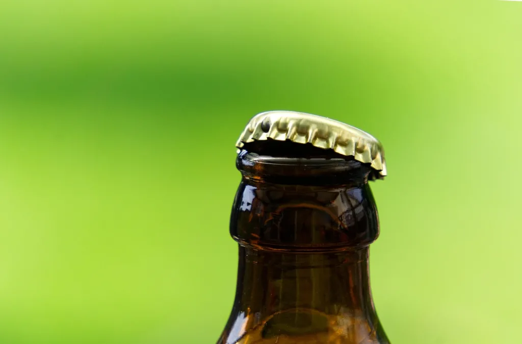 foto do bico de uma garrafa de cerveja com a tampa aberta.