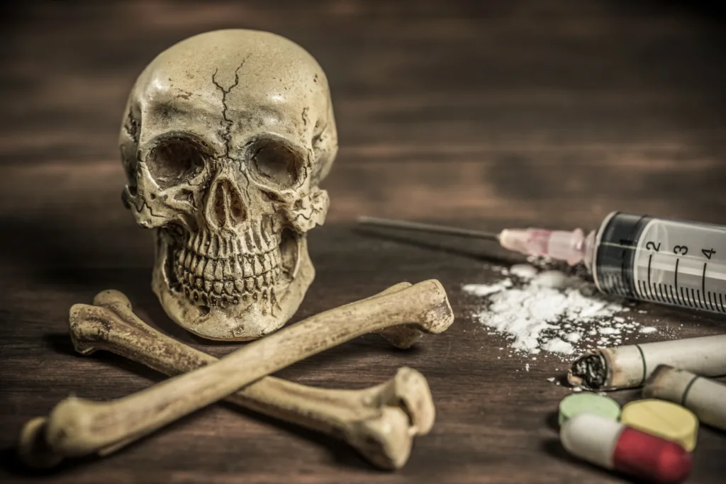 uma caveira e drogas em uma mesa de madeira.