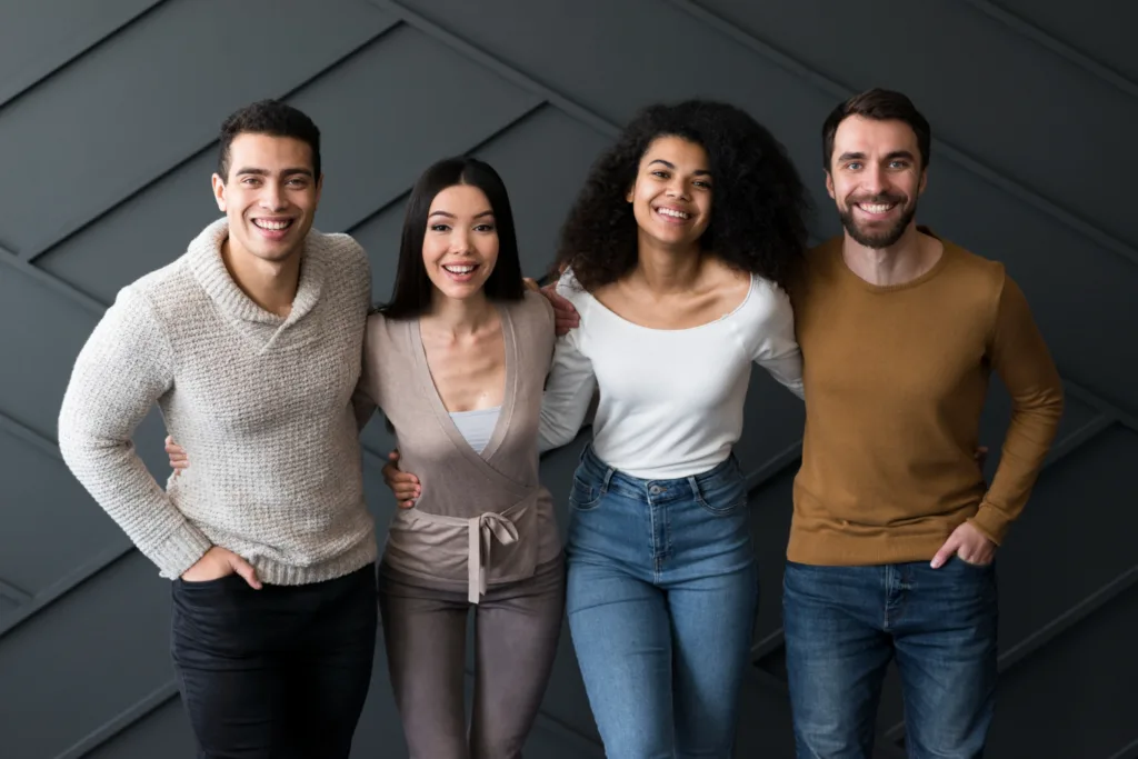 grupo de pessoas adultas jovens abraçadas lado a lado.
