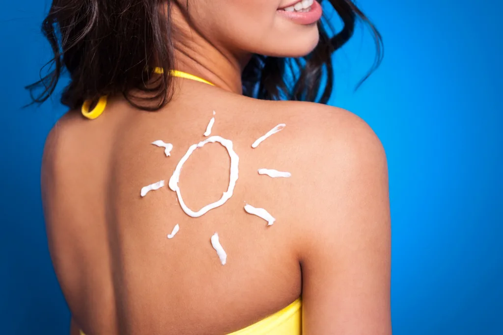 uma jovem com um desenho de um sol no ombro, com protetor solar.