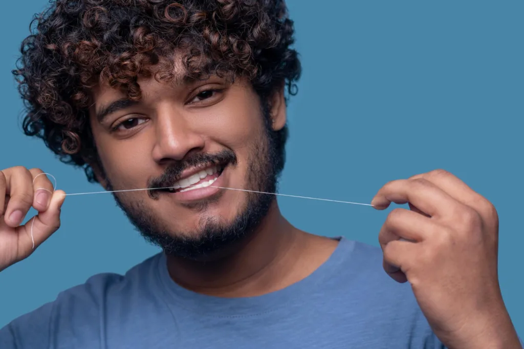 foto de um jovem usando fio dental.