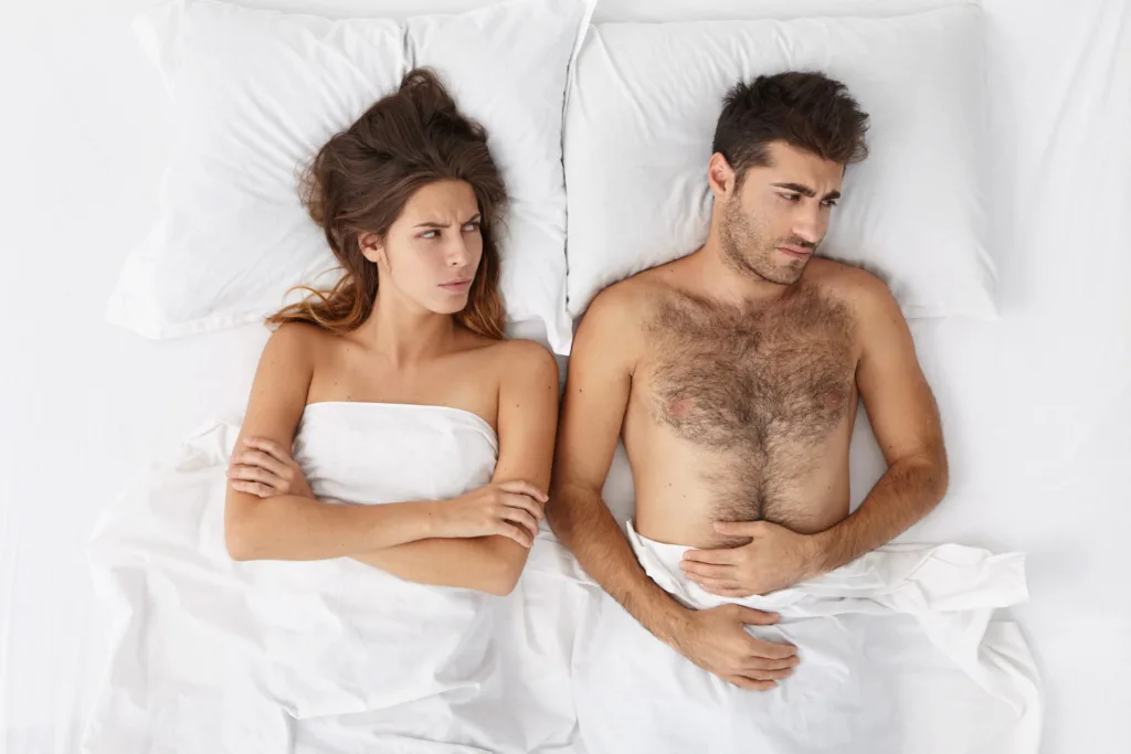 casal deitado numa cama, com problema de relacionamento.