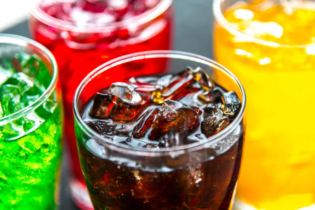 vários copos de refrigerantes de vários sabores, vistos de cima.