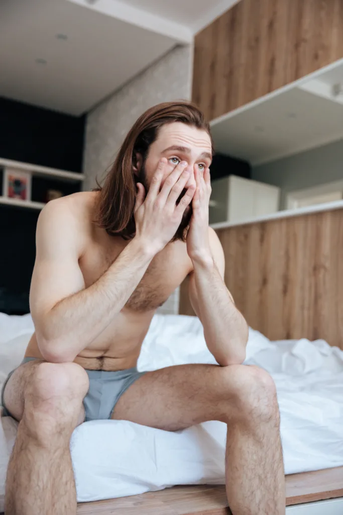 homem sentado na cama após acordar.