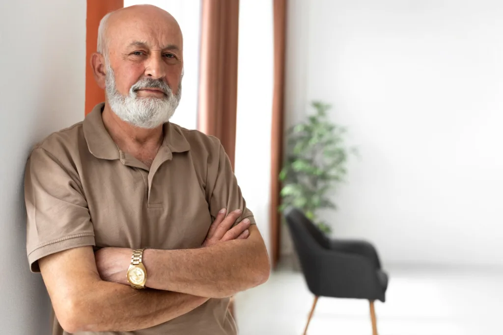 homem idoso de braços cruzados em primeiro plano.