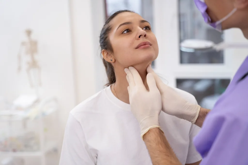 medica examinando a tireoide de uma paciente.