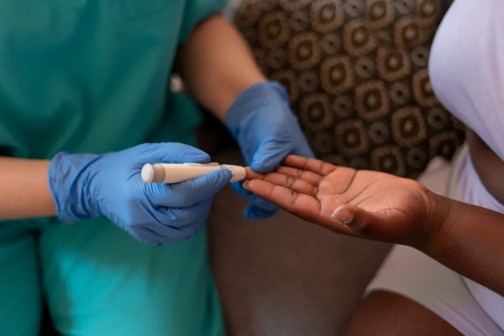 enfermeira medindo a glicemia de uma pessoa via furo no dedo.