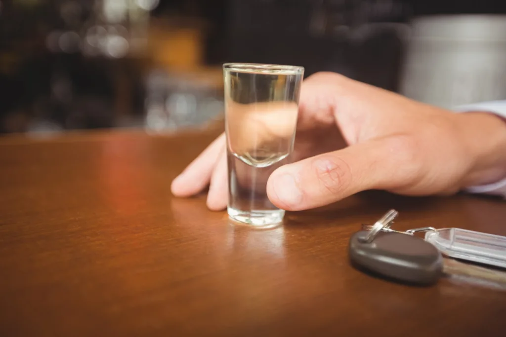 uma mão segurando um pequeno copo de bebida alcoólica.