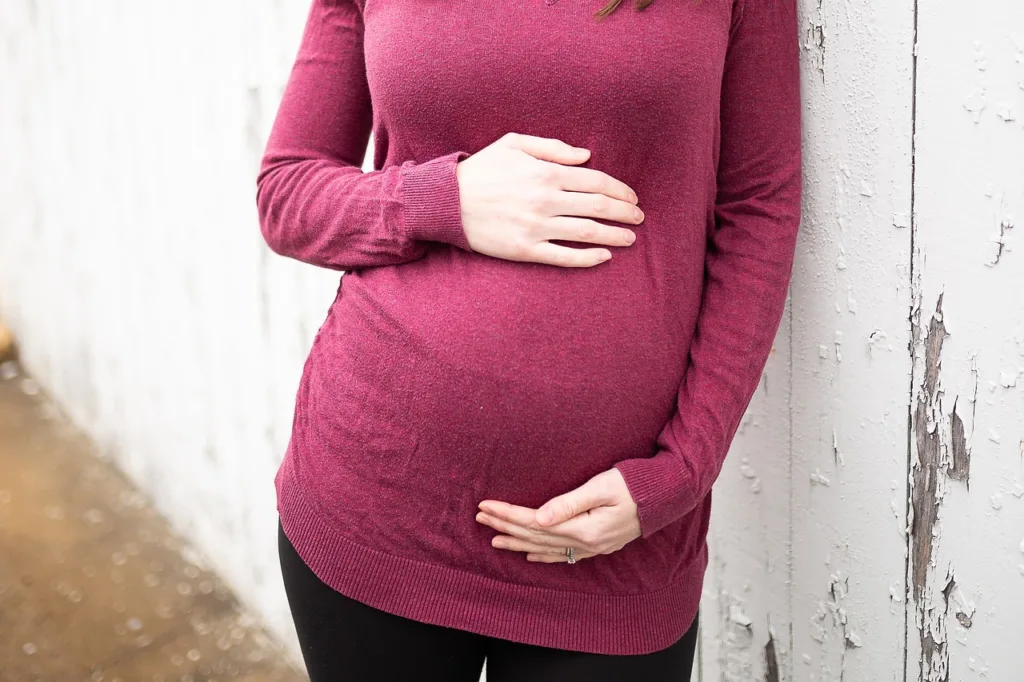 foto da barriga de uma gravida amparando a barriga com as duas mãos.