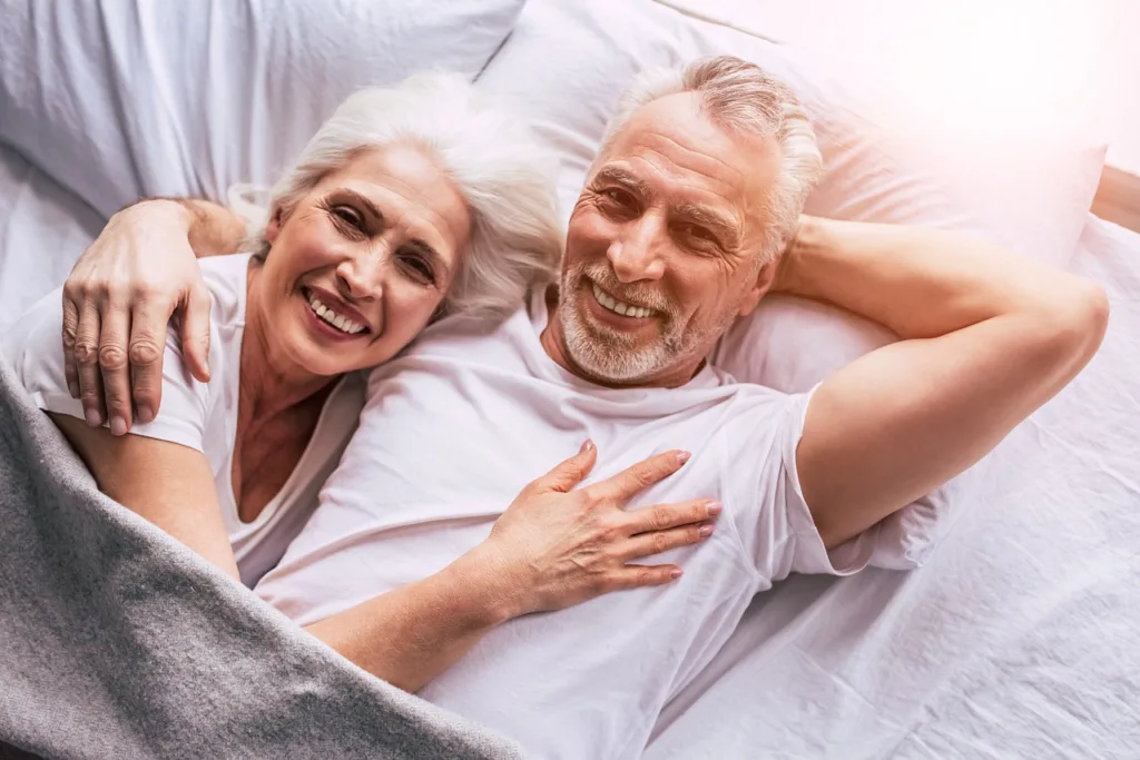 casal de idosos felizes, deitados na cama.
