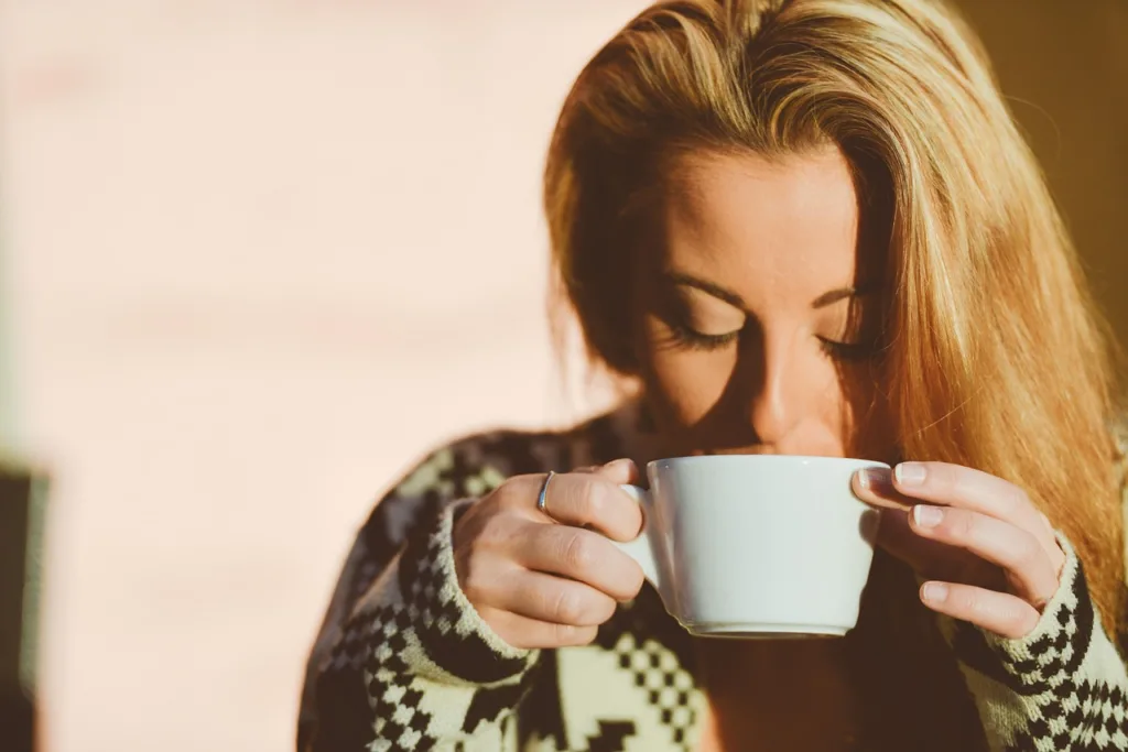 mulher saboreando uma xicara de café.