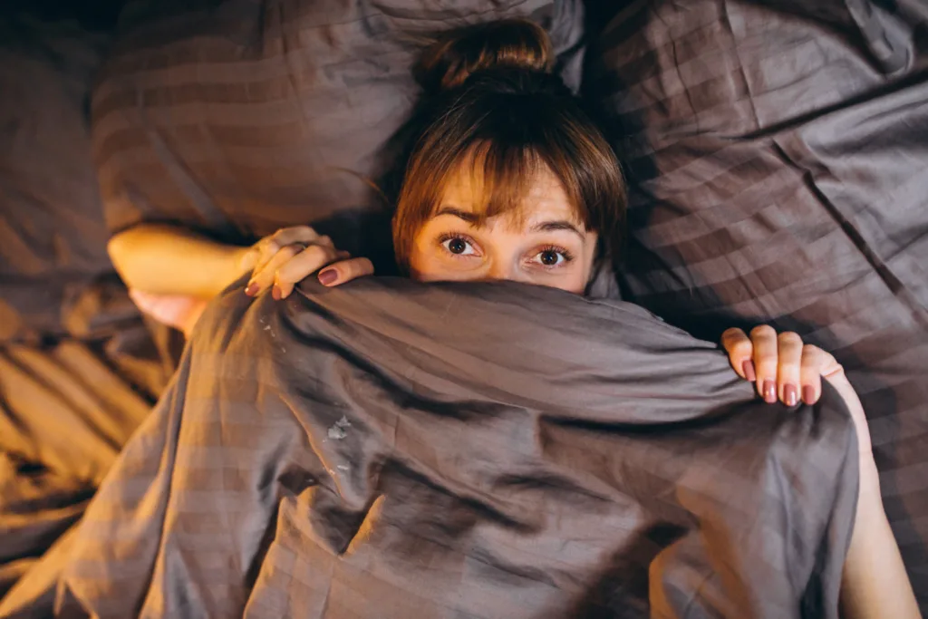 uma mulher demonstrando medo em uma cama.