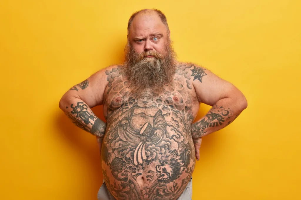 homem tatuado com uma barriga enorme.